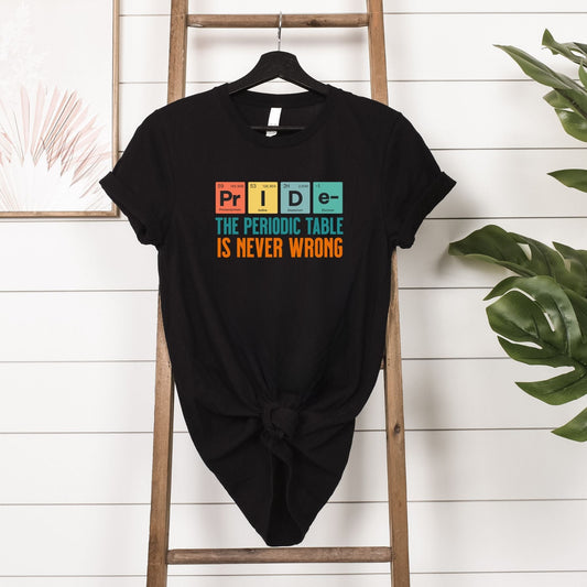 Black T-shirt with "The Periodic Table Is Never Wrong" slogan and PRIDE spelled using periodic table elements, hanging on wooden ladder.