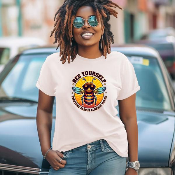 Woman wearing a Bee Yourself T-Shirt with a colorful bee graphic and sunglasses, standing outdoors smiling confidently