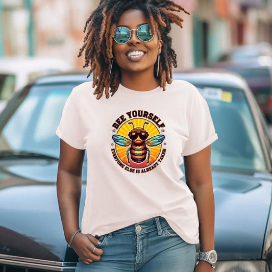 Woman wearing a Bee Yourself T-Shirt with a colorful bee graphic and sunglasses, standing outdoors smiling confidently