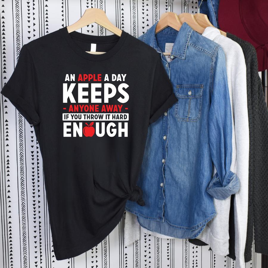 Black t-shirt with humorous apple-themed text design hanging among casual shirts