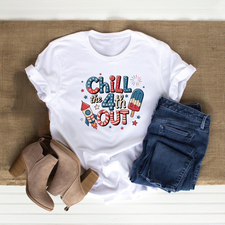 White Chill the 4th Out T-shirt with patriotic fireworks and popsicle design, paired with blue jeans and tan ankle boots