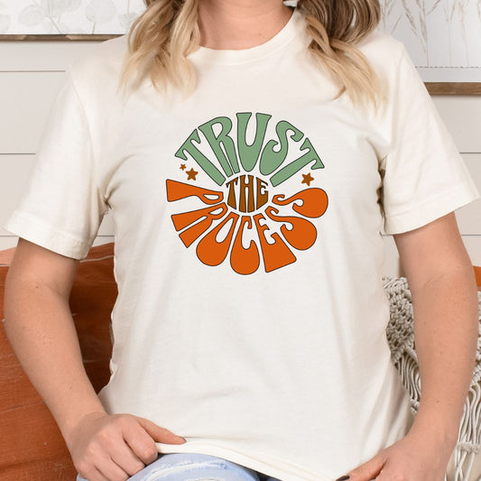 White Trust the Process T-Shirt with retro green and orange text design worn by a person sitting indoors