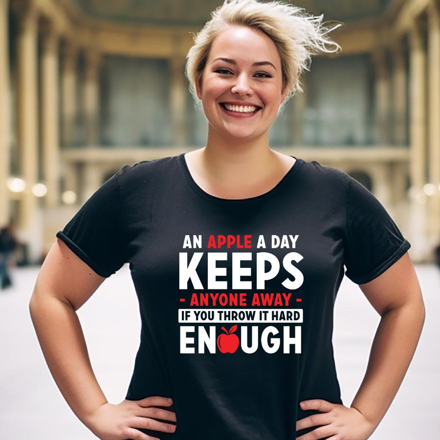 Smiling woman wearing black t-shirt with humorous "An apple a day keeps anyone away if you throw it hard enough" text and apple graphic