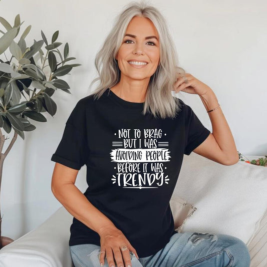 Woman wearing black t-shirt with "Not to brag but I was avoiding people before it was trendy" text design