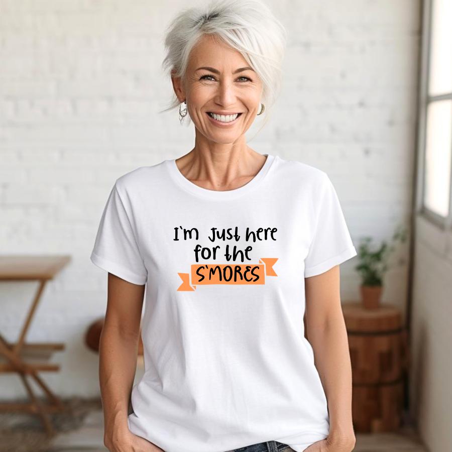Woman smiling wearing white t-shirt with "I'm Just Here for the S'mores" text, perfect for campfires and winter fireplaces
