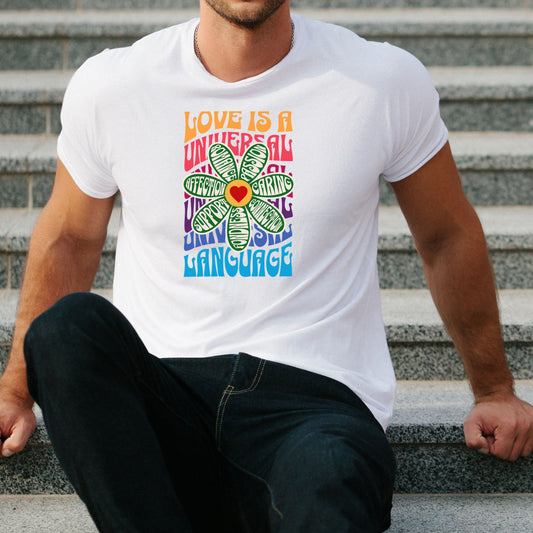 Man wearing white Love is a Universal Language T-shirt with colorful text and heart design sitting on stairs