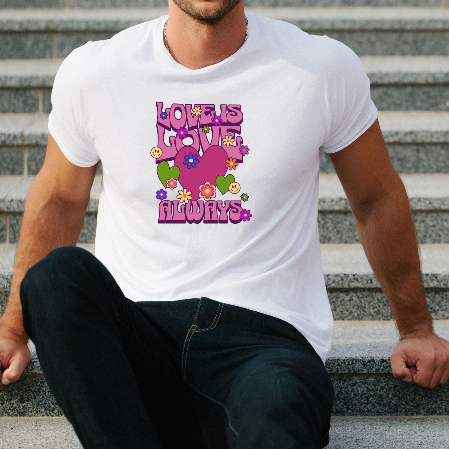 White t-shirt with colorful "Love is Love Always" graphic featuring hearts and flowers, worn by seated man.