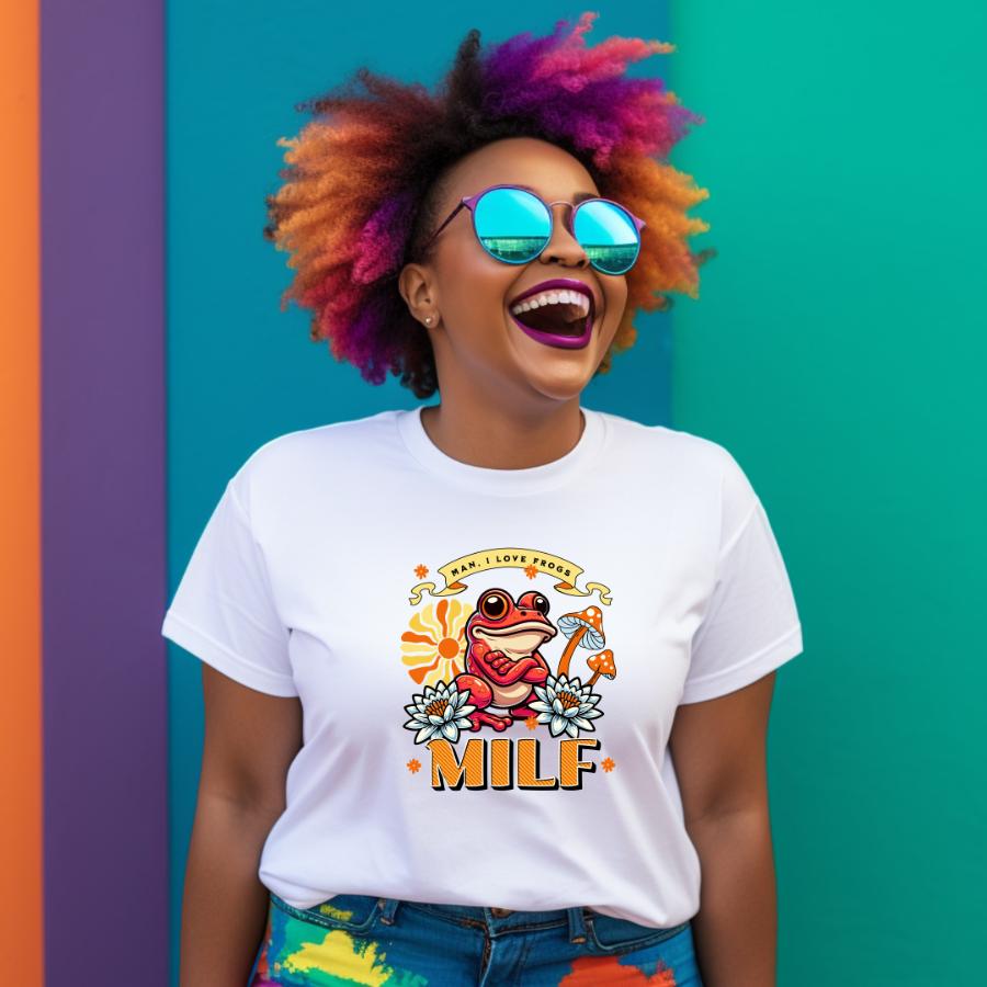 Woman wearing a white Man I Love Frogs T-shirt with colorful frog graphic and text MILF, smiling against a vibrant teal and purple background