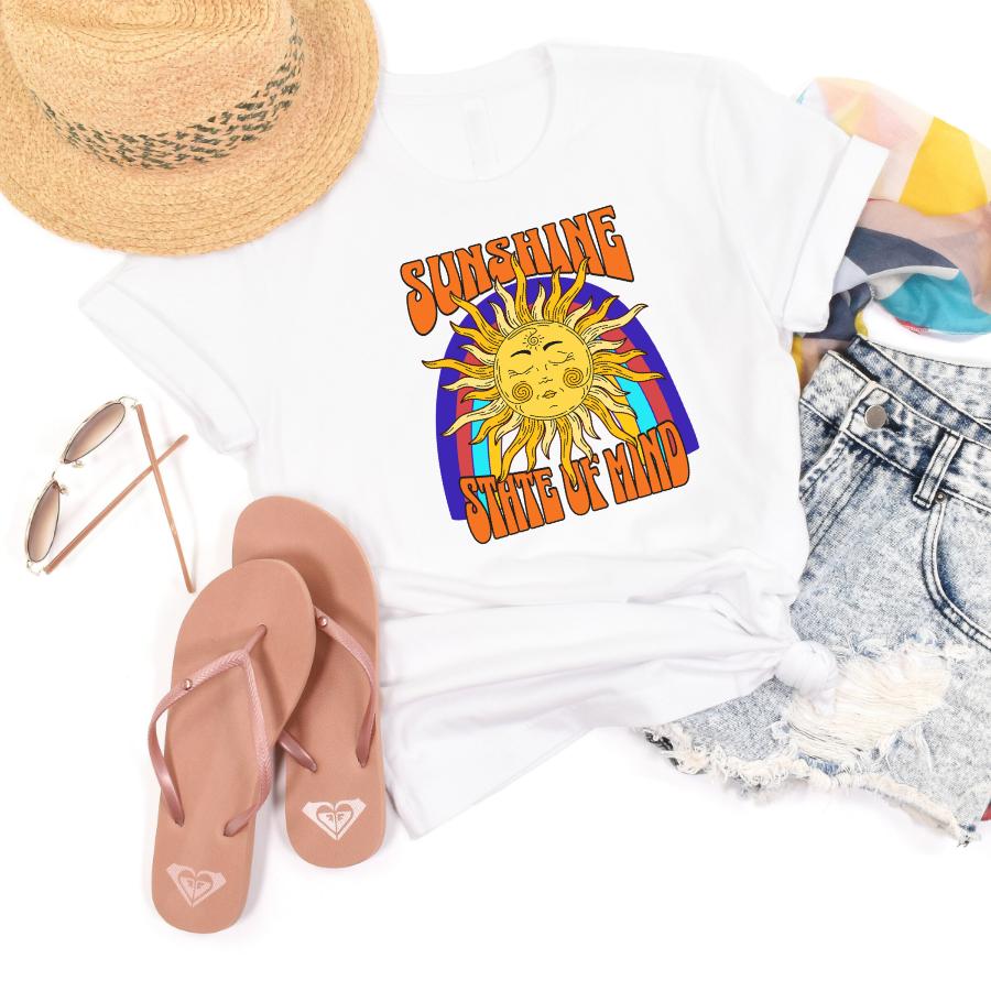 White Sunshine State of Mind T-shirt with sun graphic, paired with denim shorts, pink flip-flops, straw hat, sunglasses, and colorful scarf for summer style